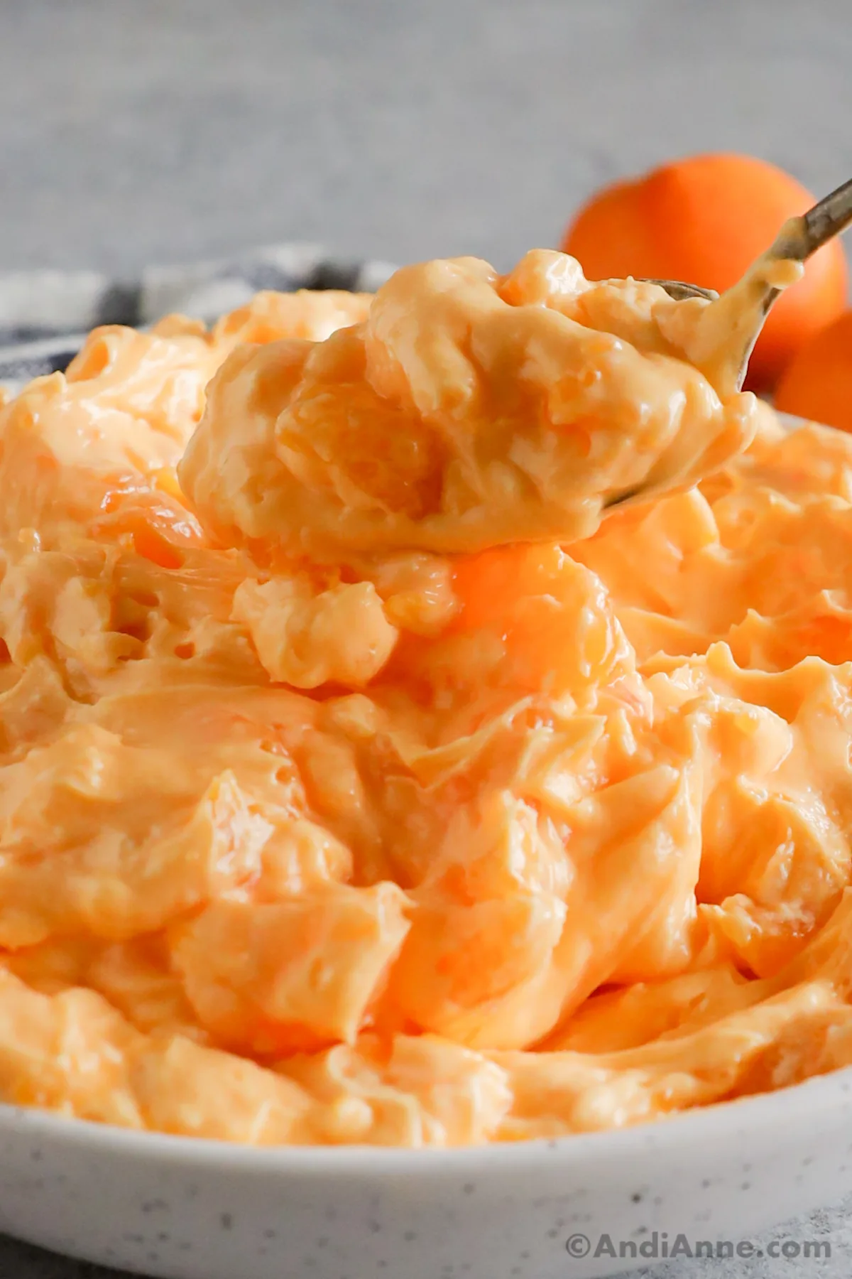 Close up of a spoon scooping orange jello salad.