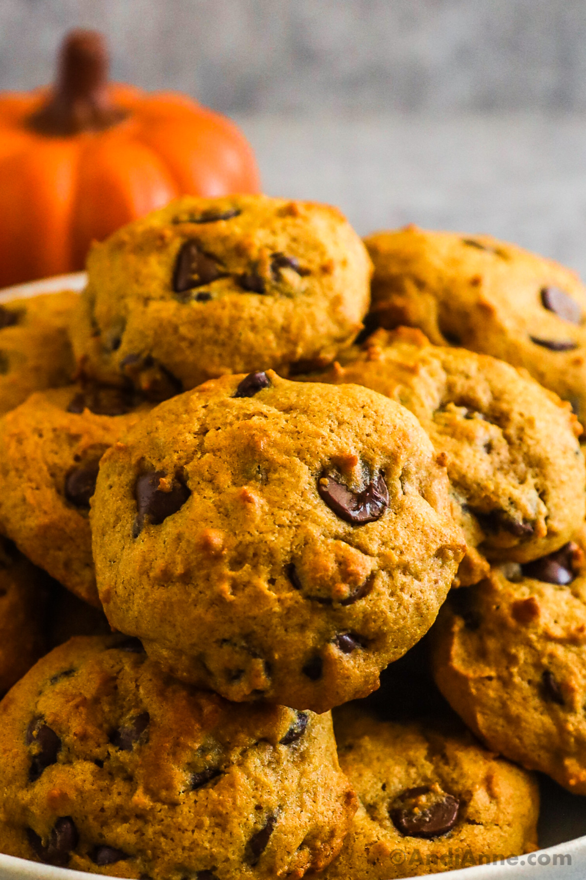 A stack of pumpkin chocolate chip cookies on a plate.