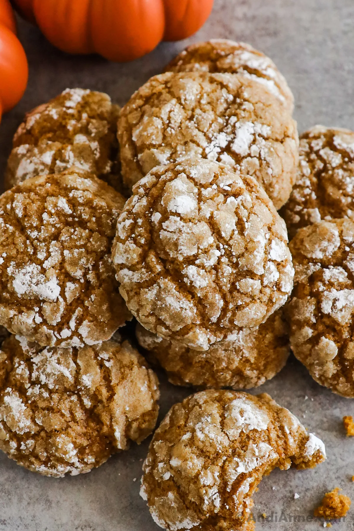 A stack of pumpkin crinkle cookies, one with a bite taken out of it.