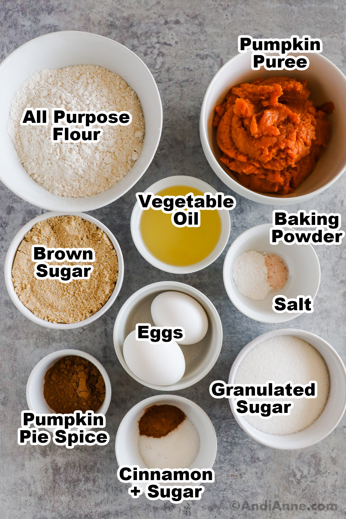 Recipe ingredients, all in bowls including flour, pumpkin puree, brown sugar, vegetable oil, baking powder, salt, eggs, granulated sugar and pumpkin pie spice.