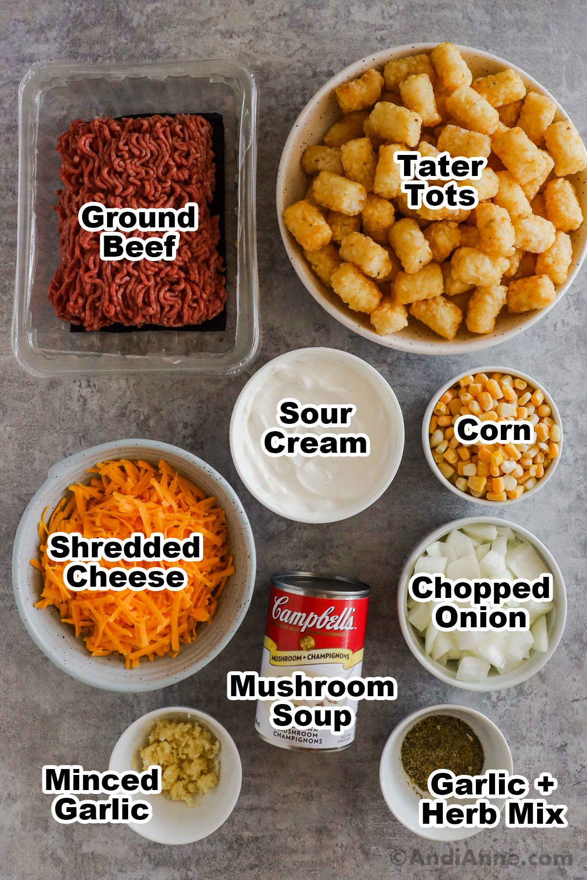 overhead view of all the ingredients in separate bowls: Ground Beef, Tater Tots, Sour Cream, Corn, Shredded Cheese, Mushroom Soup, Chopped Onion, Minced Garlic, Garlic and Herb Mix