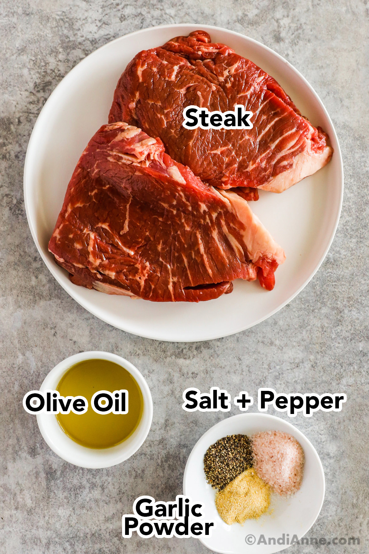 Raw steaks on a plate, bowl of olive oil, salt and pepper, and garlic pepper.