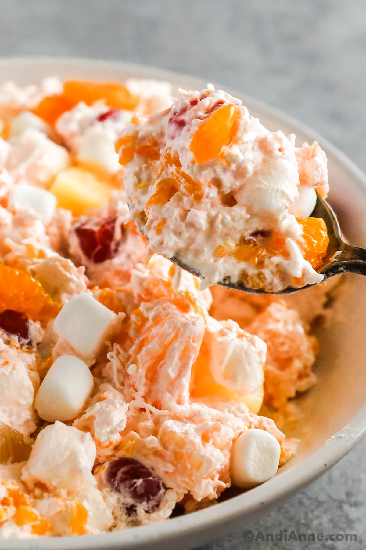 Close up of a spoon holding serving of ambrosia salad.