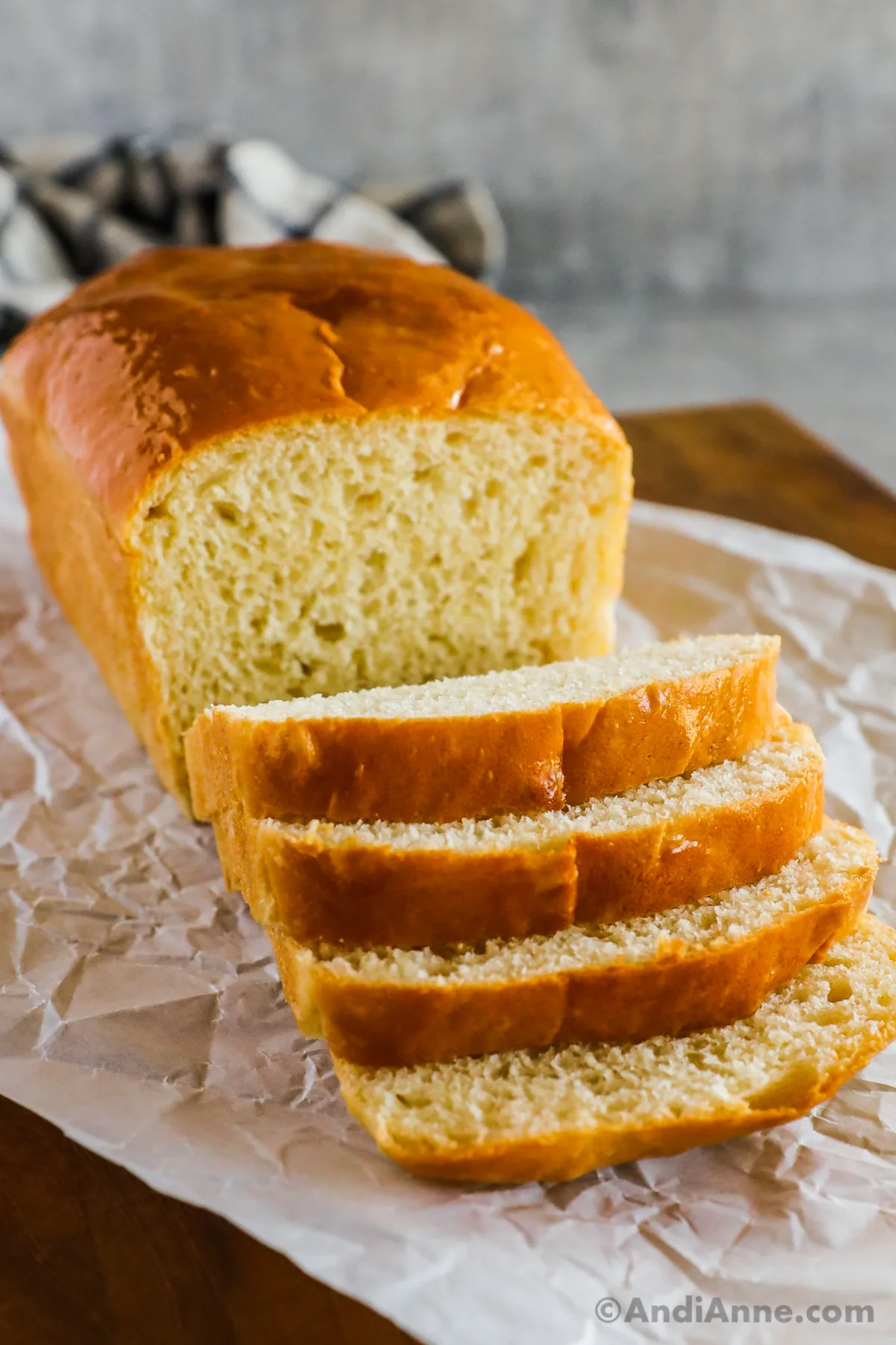 Sliced white bread loaf on crinkled parchment paper.
