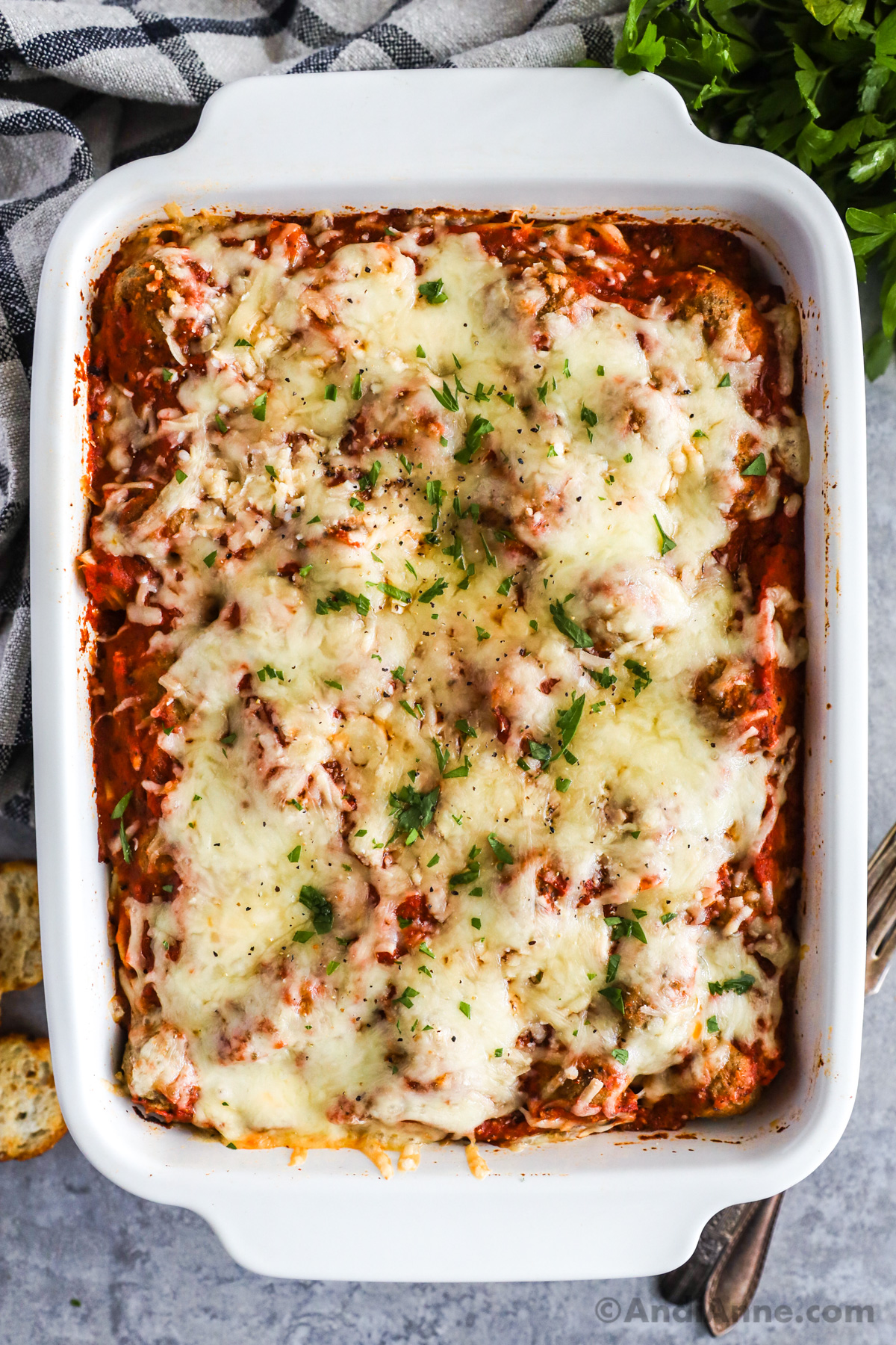 A casserole dish with baked spaghetti and meatballs topped with melted cheese.