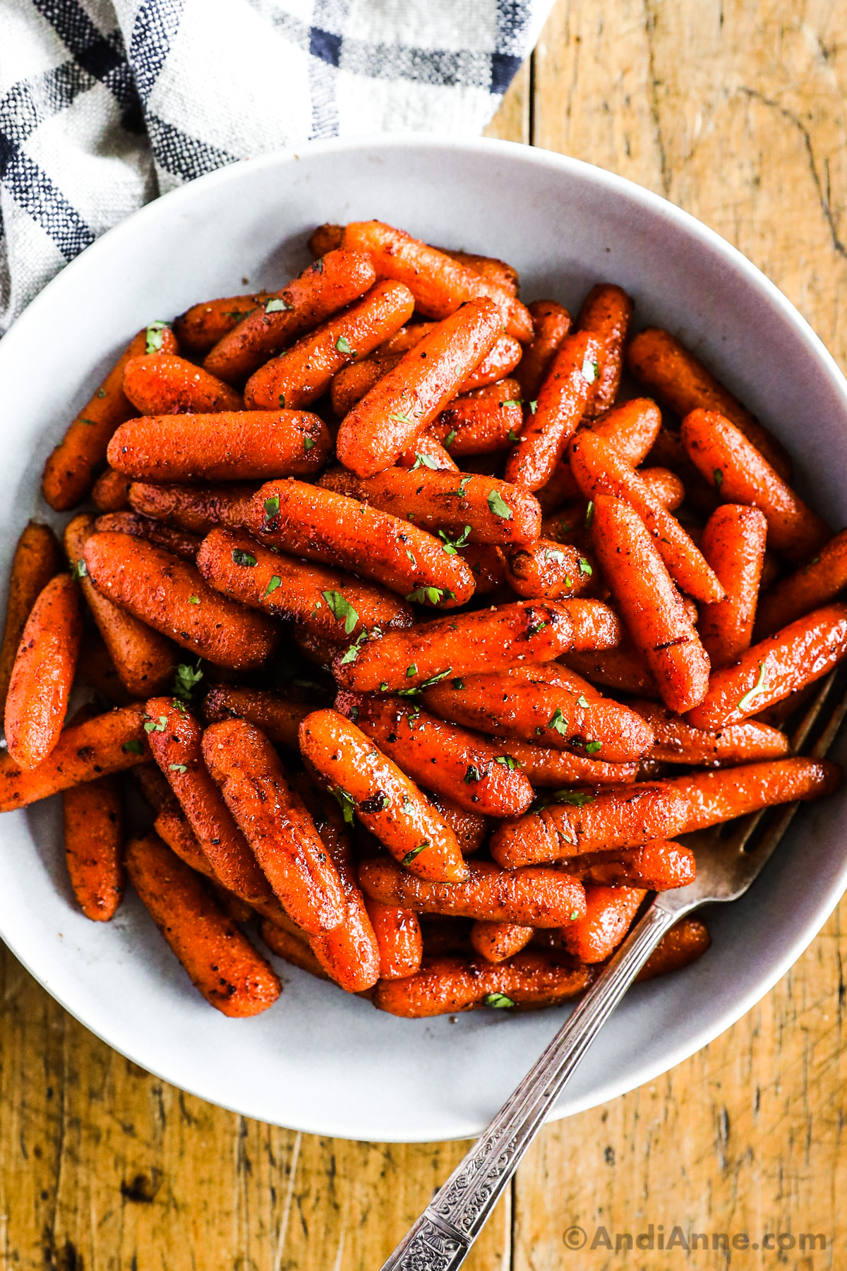 A bowl of brown sugar roasted baby carrots with a sprinkle of chopped parsley.