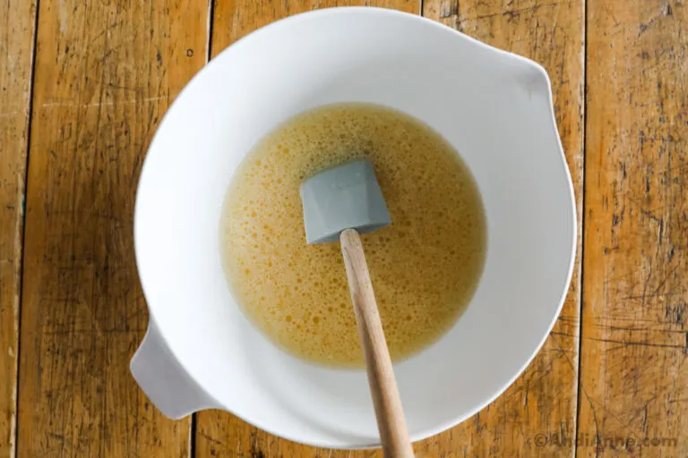 A bowl with liquid ingredients and spatula.