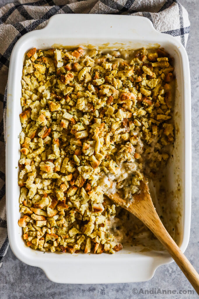 Chicken stuffing bake recipe in a white baking dish with a wood spoon.