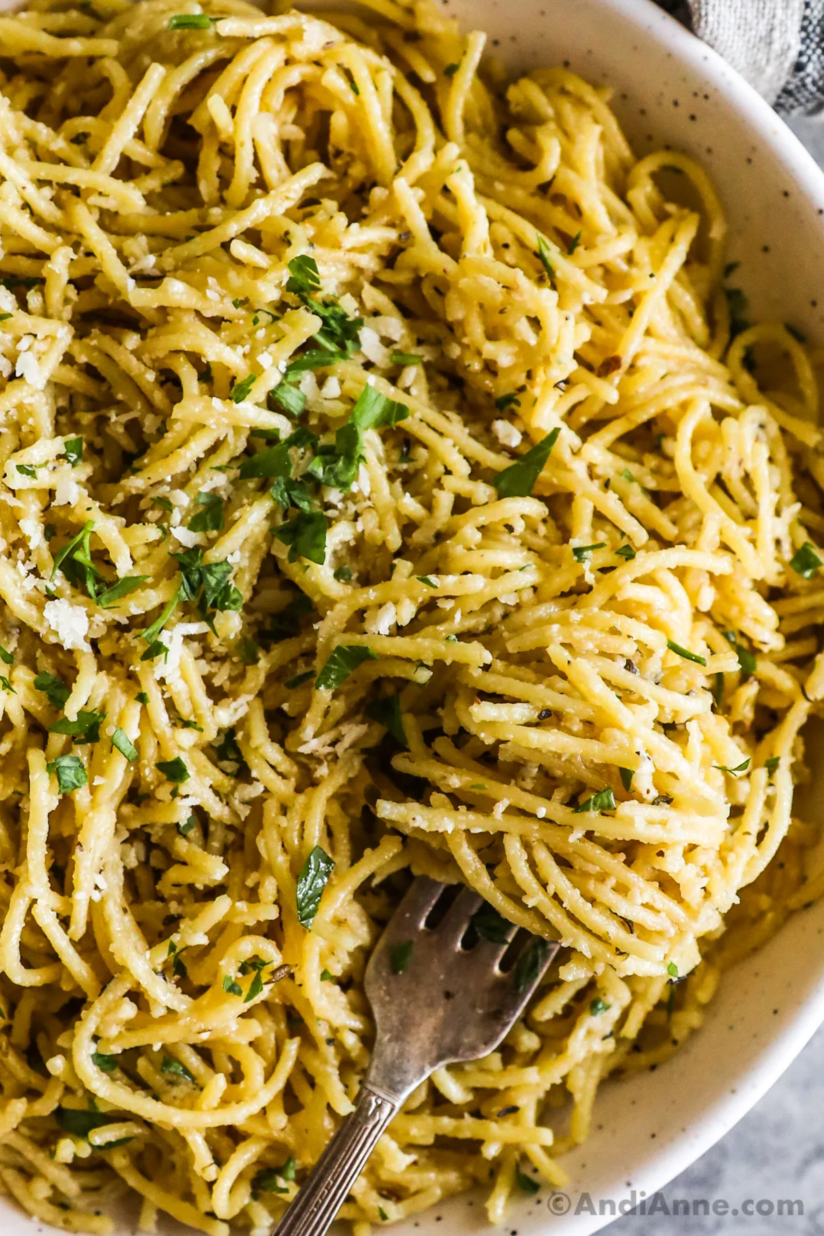 Close up of garlic parmesan pasta noodles sprinkled with chopped parsley.