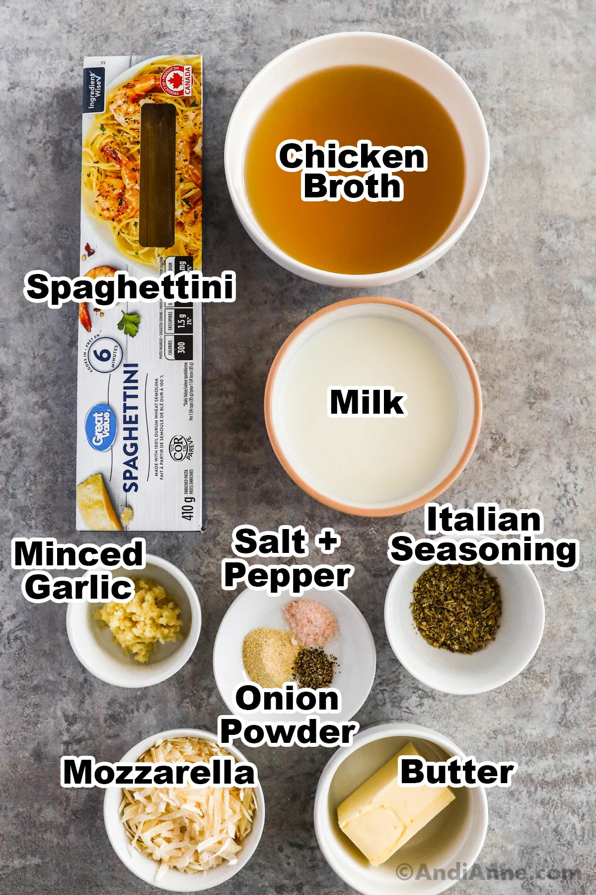 Recipe ingredients on counter including box of spaghettini, bowls of chicken broth, milk, minced garlic, italian seasoning, spices, butter and parmesan cheese.