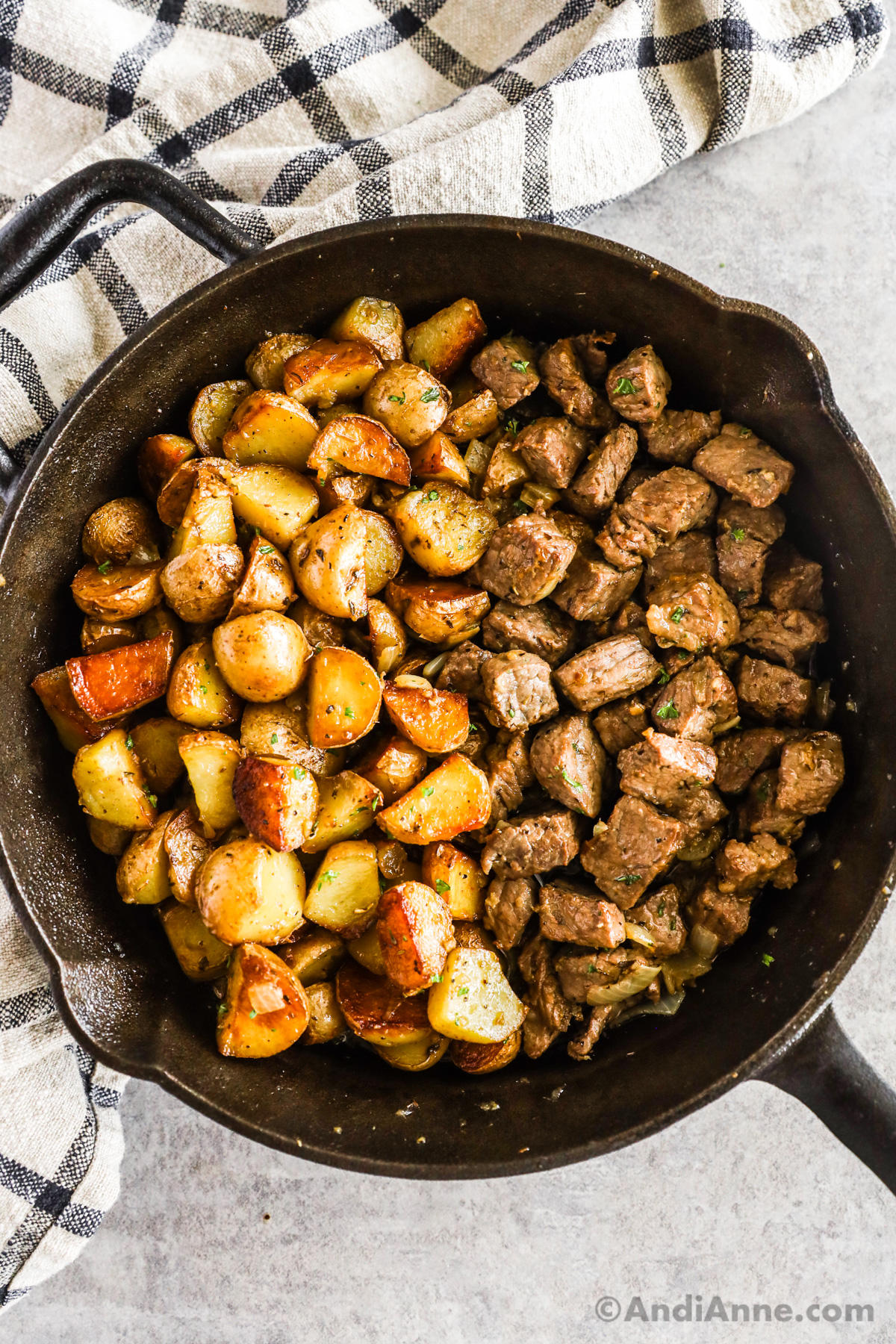Frying pan with cooked mini potatoes and steak bites.