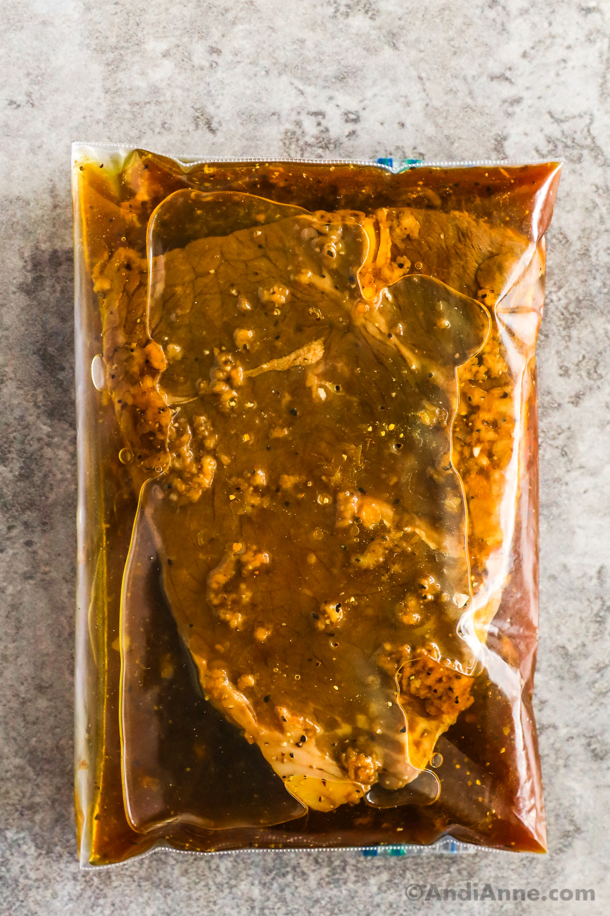 Close up of steak and marinade inside a plastic bag.