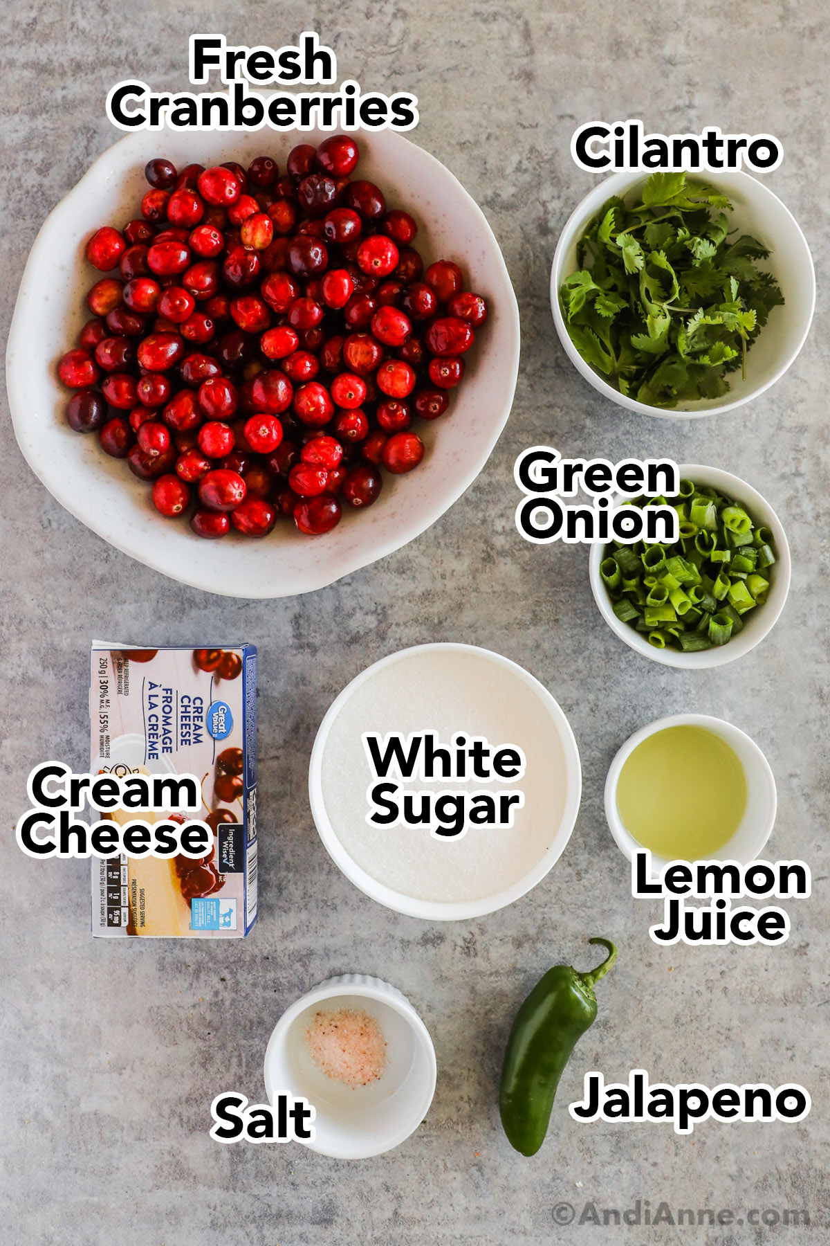 Recipe ingredients including bowls of cranberries, cilantro, green onion, cream cheese, white sugar, lemon juice, salt and a jalapeno.