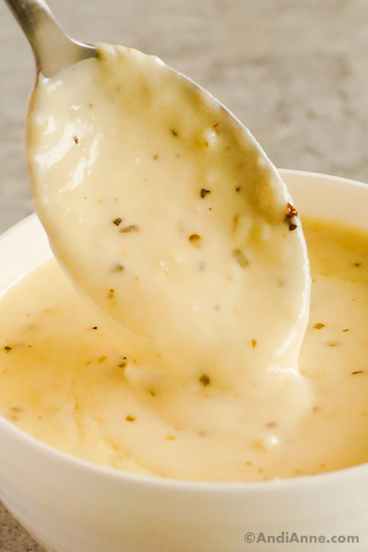 spoon pouring garlic parmesan sauce into bowl