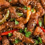 close up of mongolian beef recipe with strips of cooked steak and bell pepper coated in sauce.