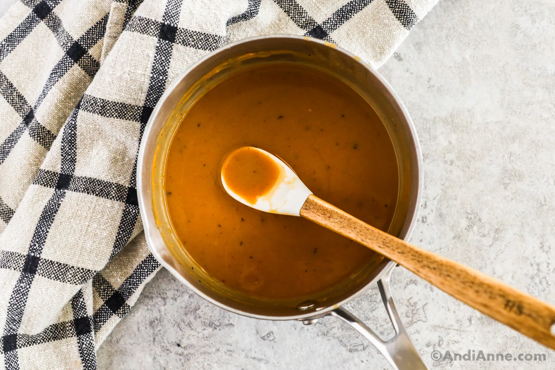 Small sauce pan with gravy and a spoon.