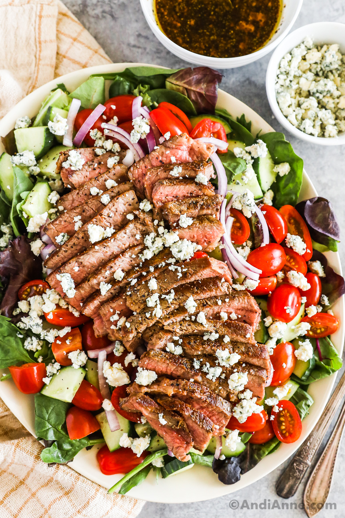 Steak salad recipe with slices of steak, crumbled blue cheese and chopped vegetables.
