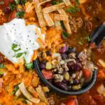 Close up of ground beef taco soup topped with cheese, sour cream and taco strips