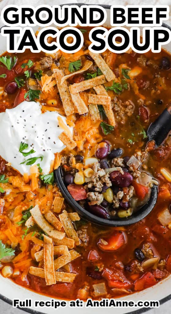 Close up of ground beef taco soup topped with cheese, sour cream and taco strips