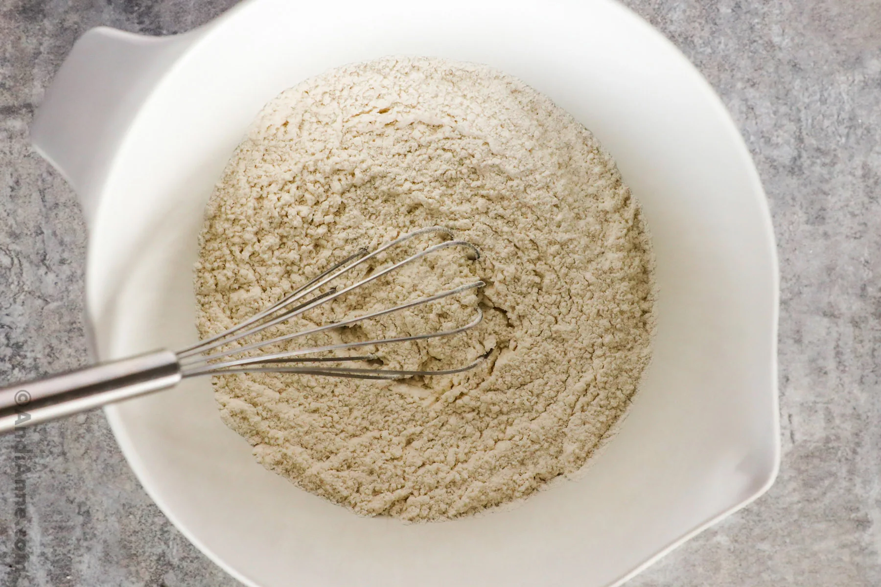 A bowl with flour and a whisk.