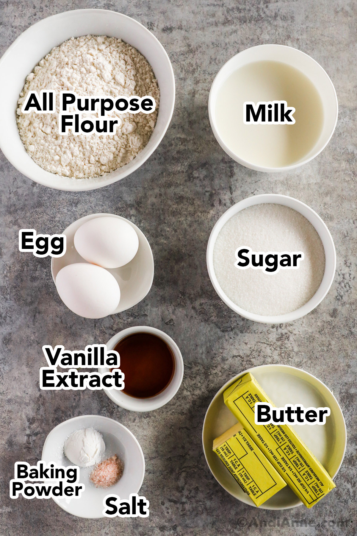 Recipe ingredients in bowls including flour, milk, eggs, sugar, vanilla, baking powder, and butter.