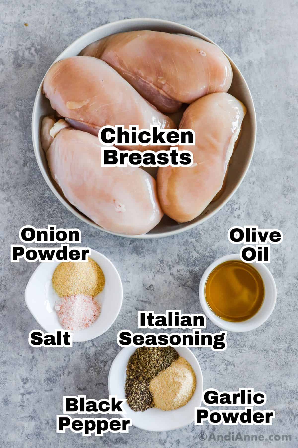 A plate of chicken breasts and small bowls of olive oil, onion powder, salt, italian seasoning, garlic powder and black pepper.