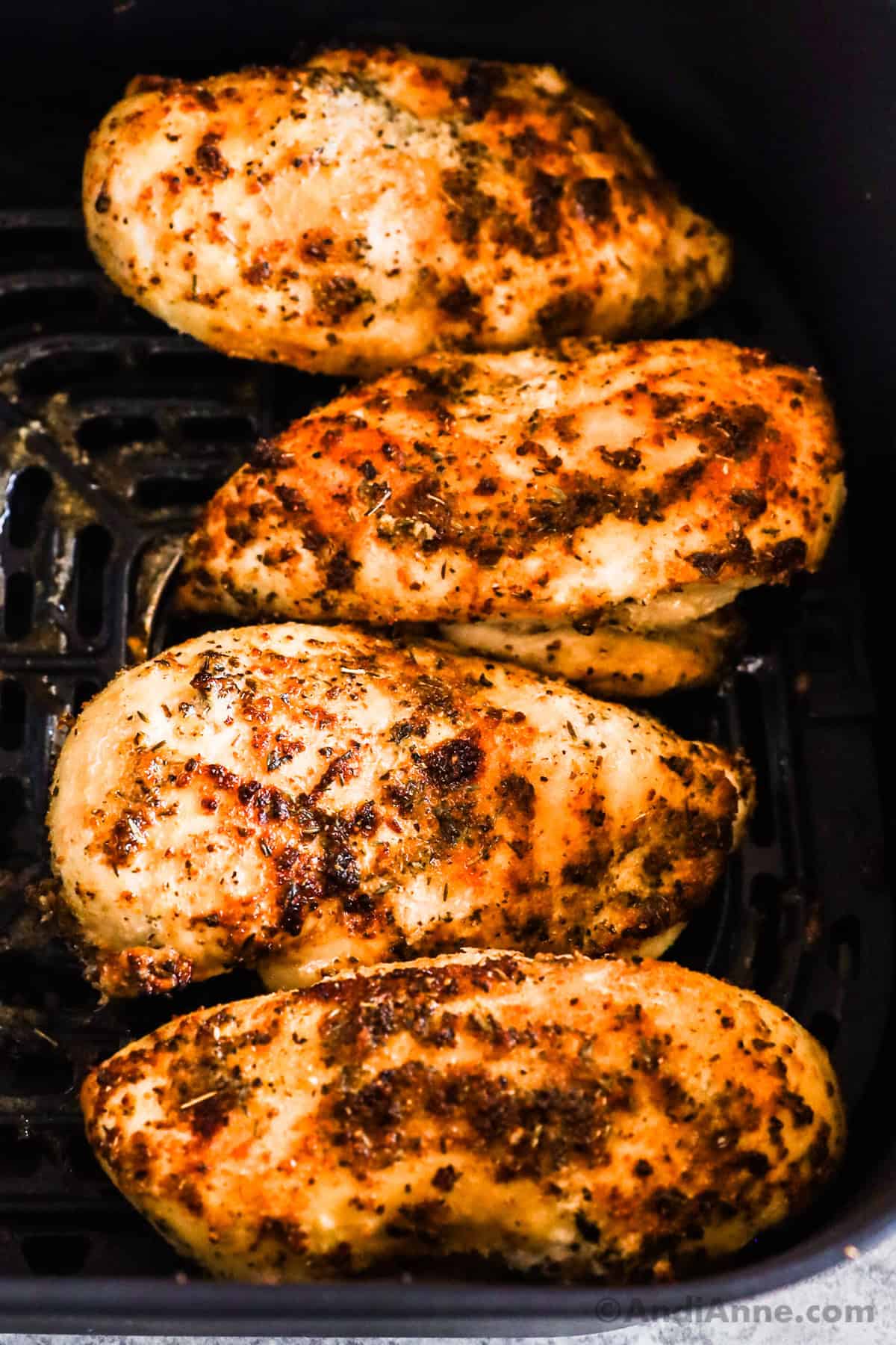 Four cooked chicken breasts in an air fryer