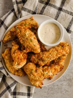 A plate with air fryer chicken tenders and a small bowl of ranch dressing
