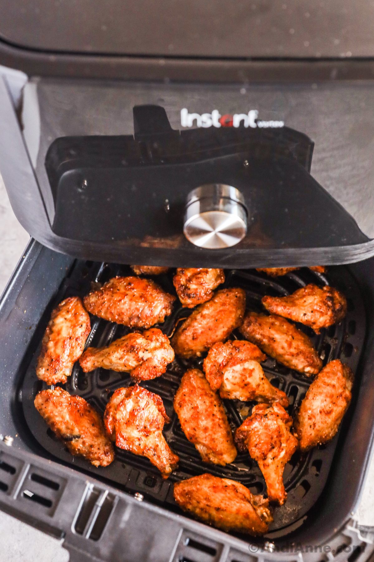 Close up of chicken wings in an air fryer basket.