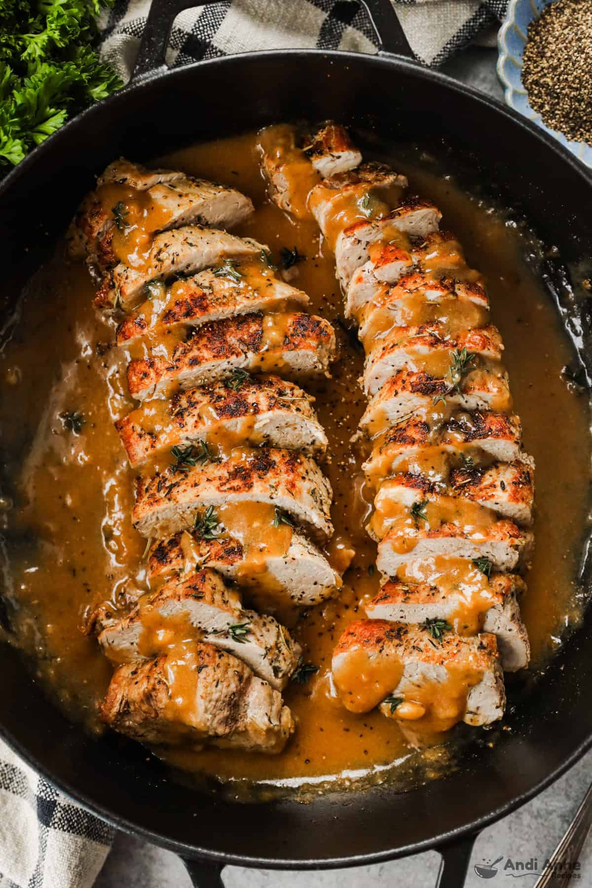 A cast-iron skillet with sliced pork tenderloin in a pan gravy.