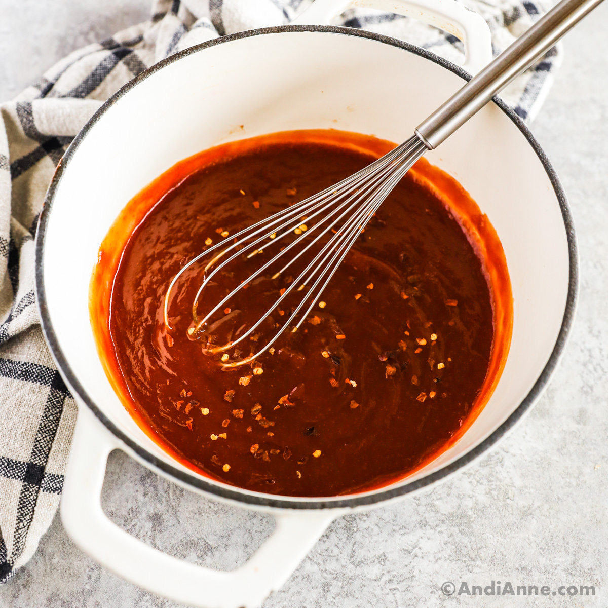 Pot of sweet and sour sauce with a whisk.