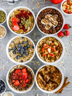 Six bowls of flavored oats with different topping ingredients including fruits, seeds and nut butter.