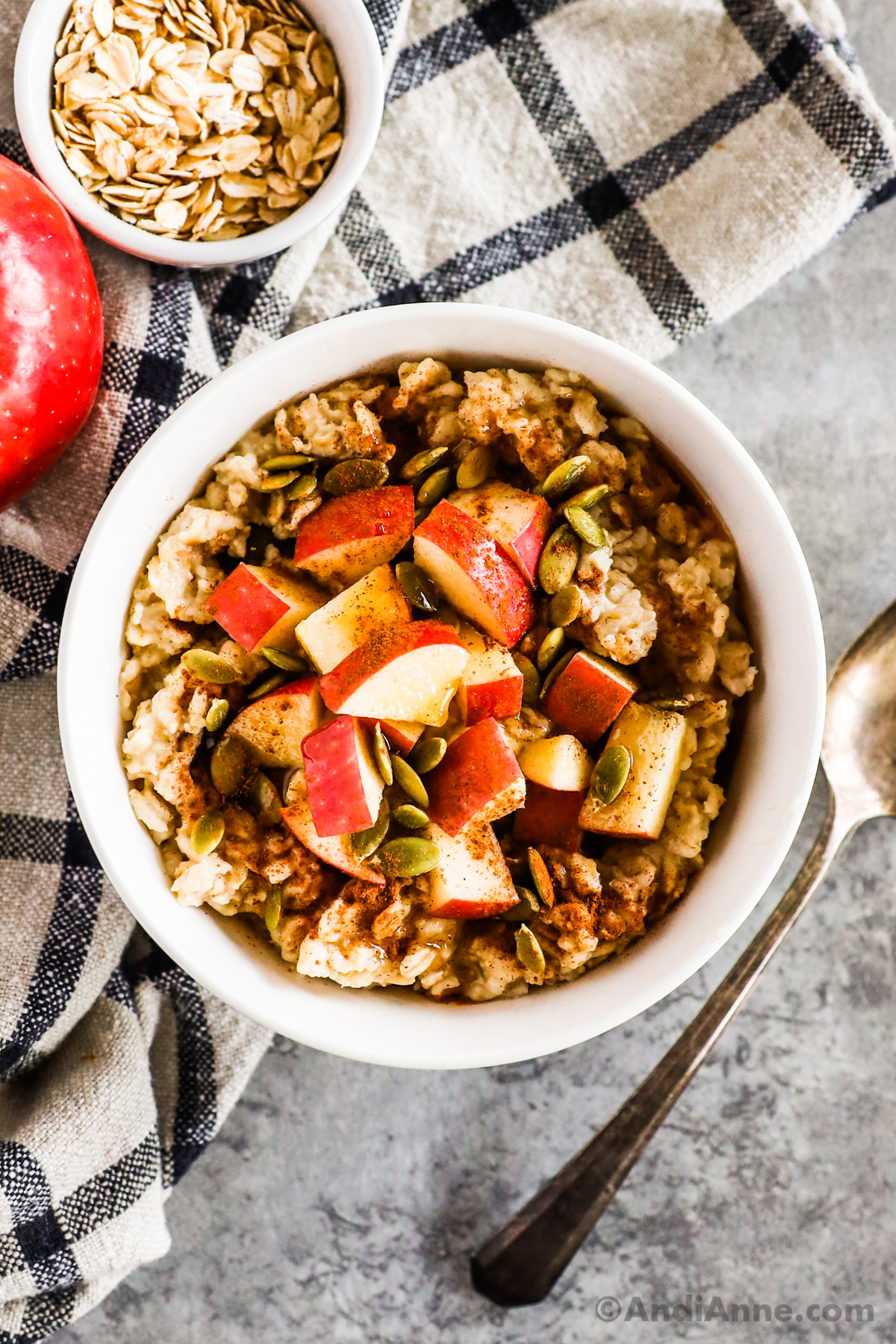 Bowl of apple cinnamon oatmeal topped with chopped apple.