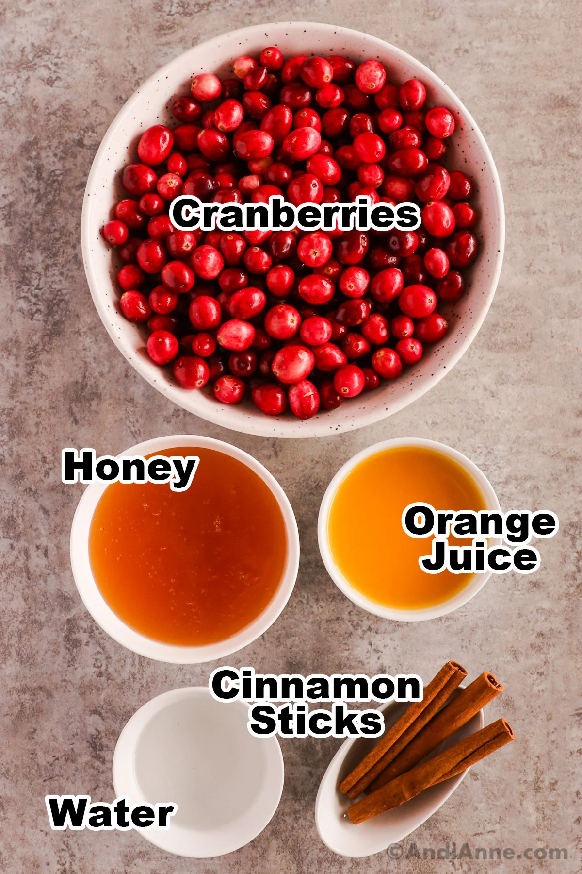 Bowls of fresh cranberries, honey, orange juice, water and cinnamon sticks.