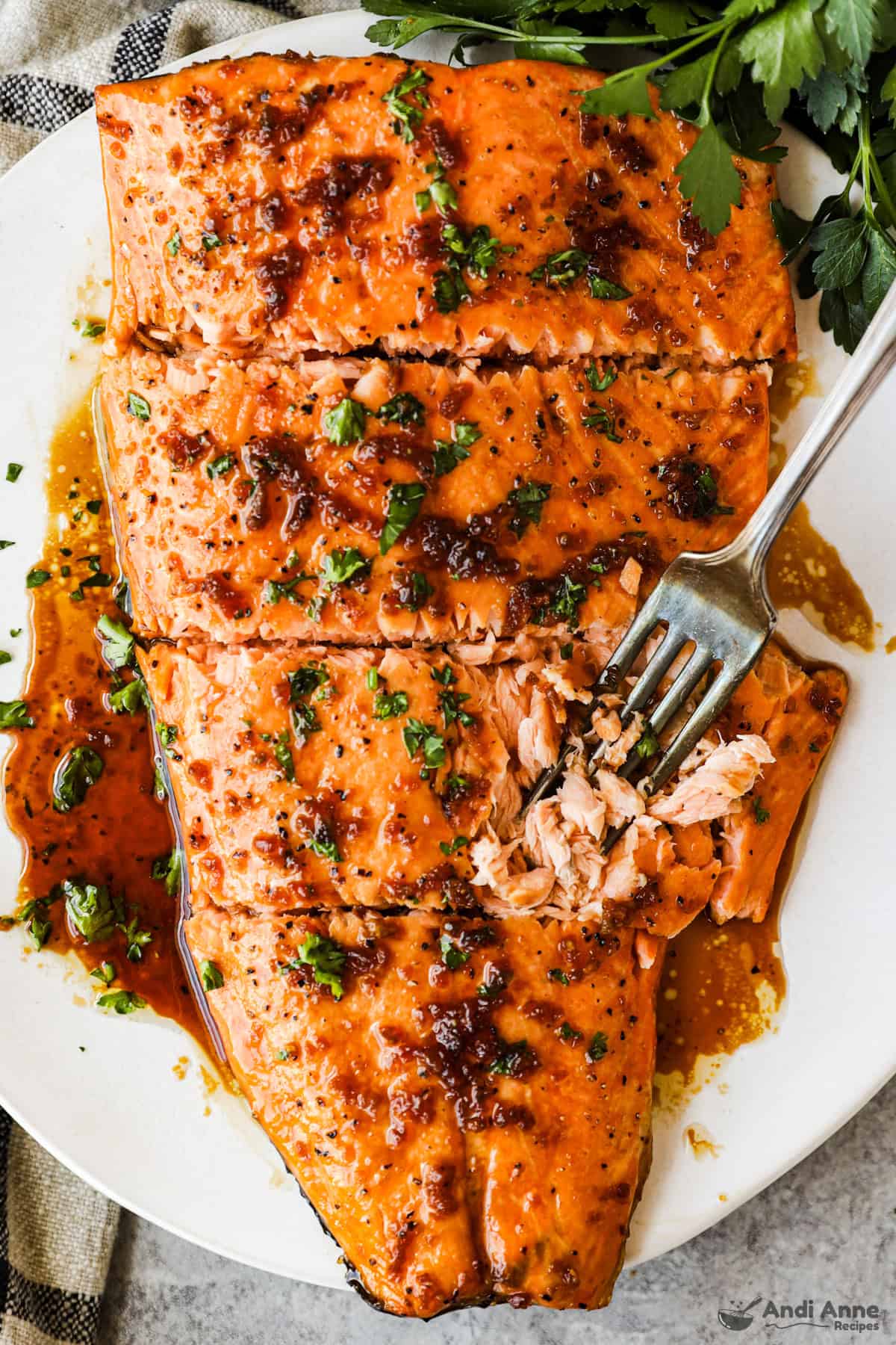 A cooked salmon fillet with sauce and a fork