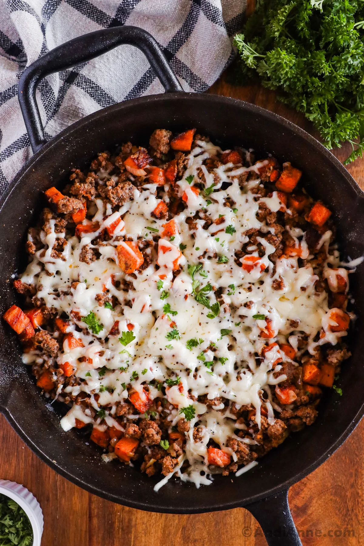 Close up of a skillet with ground beef sweet potato and melted cheese on top.