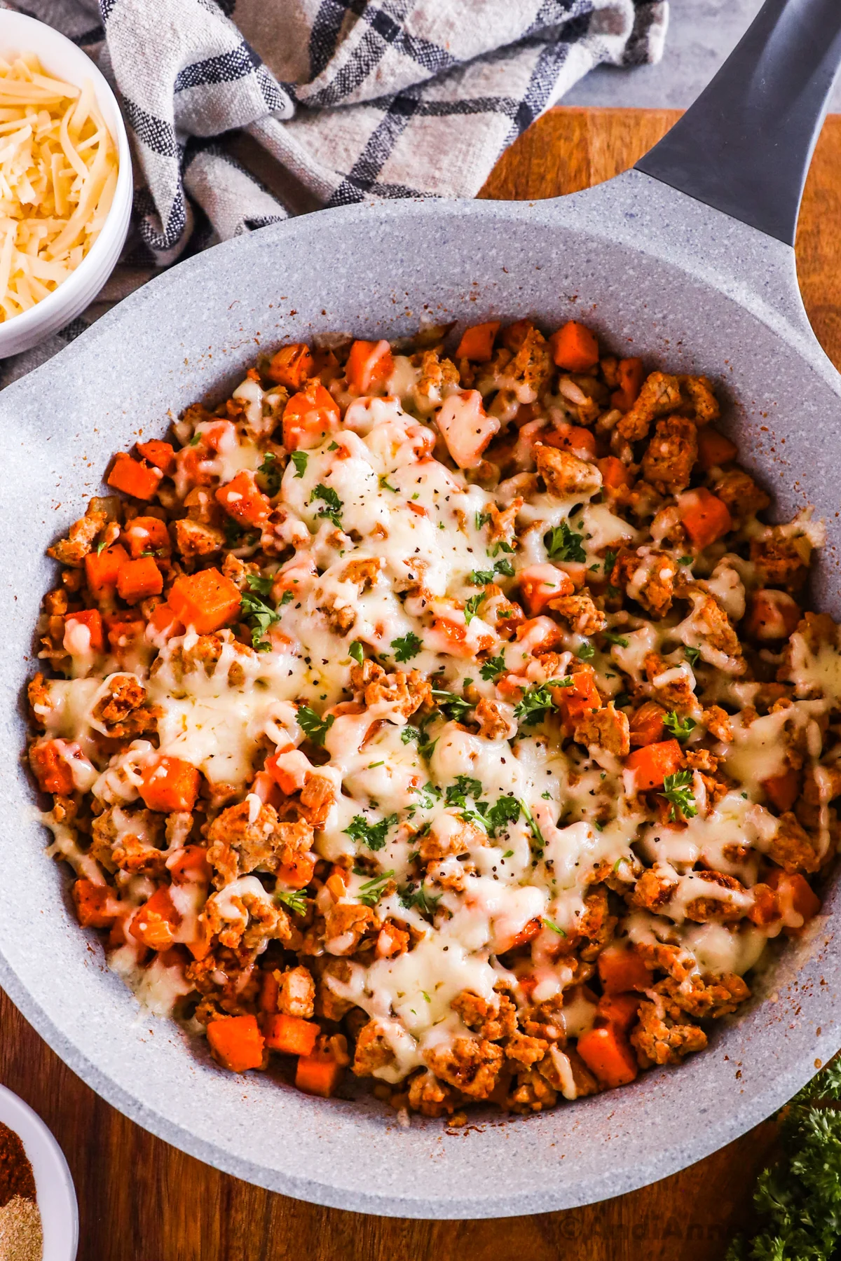 A frying pan with ground turkey, sweet potato recipe topped with melted cheese.