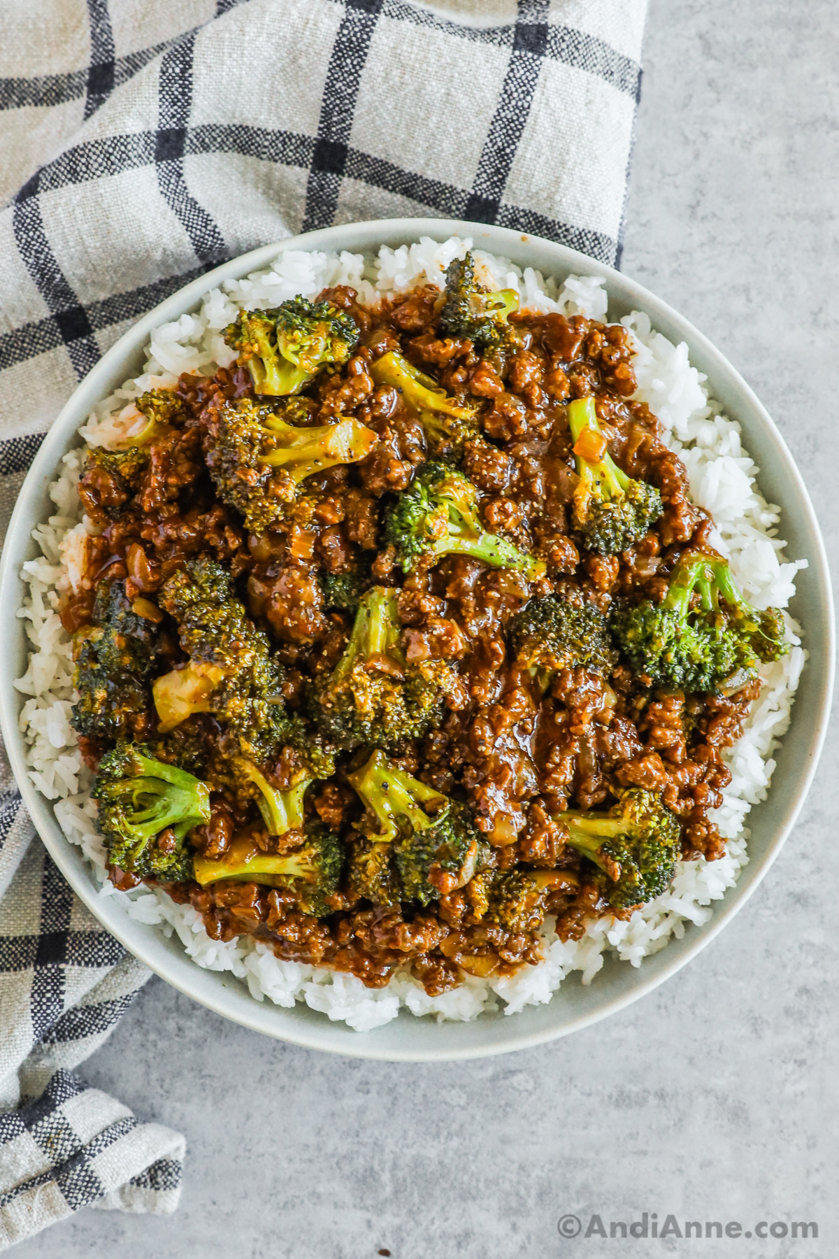 A plate of rice topped with honey garlic sauce with ground beef and broccoli florets.