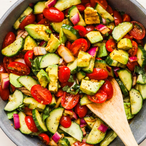 A bowl of salad with chopped avocado, tomato and cucumber.