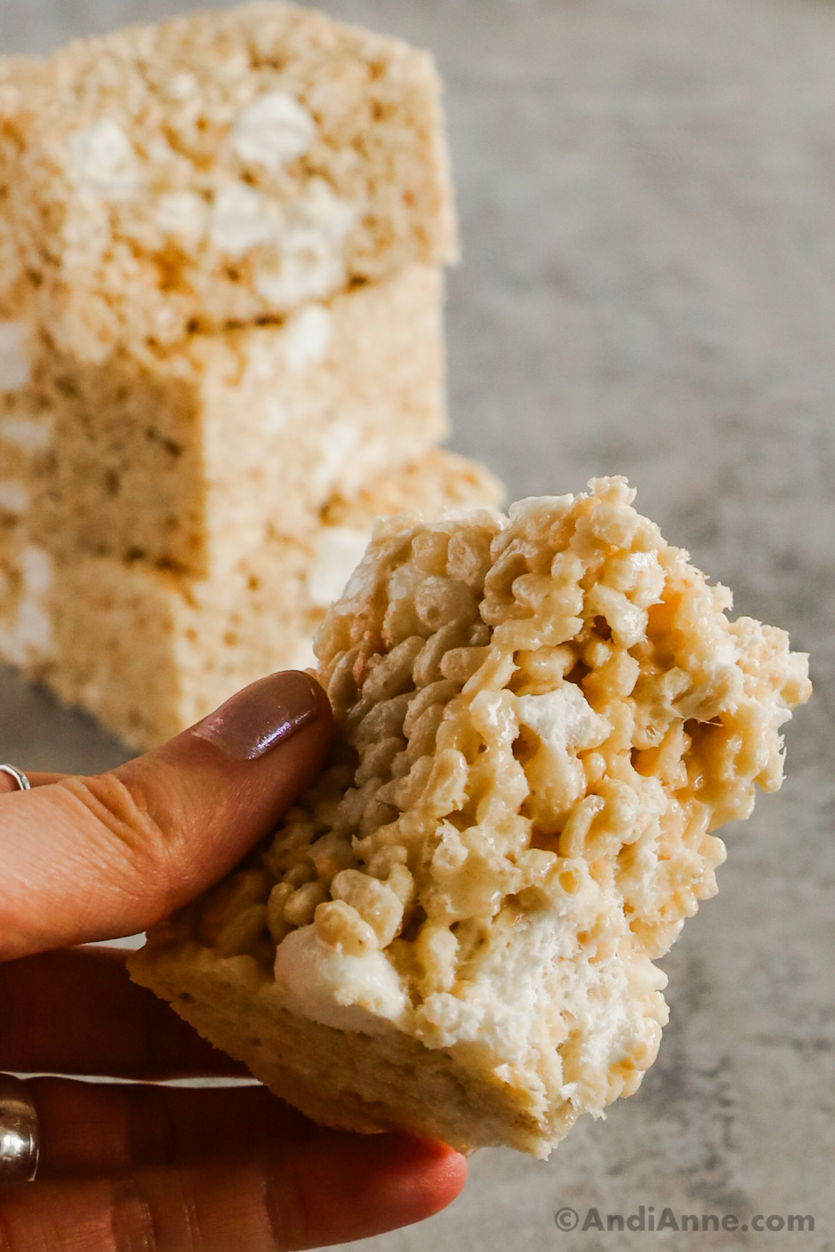A hand holding half of a rice krispie treat.