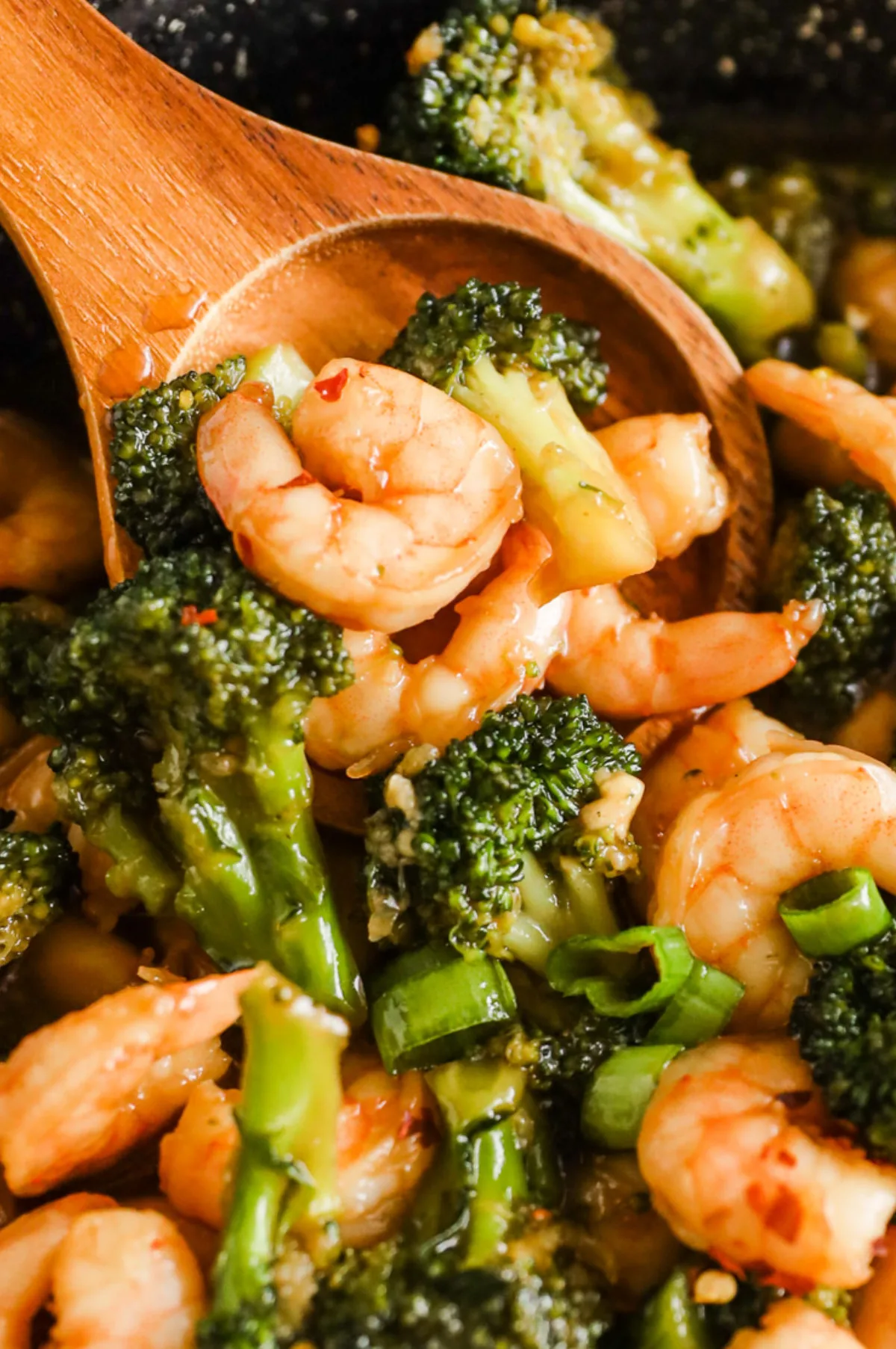 Closeup of shrimp and broccoli on a wooden spoon. 