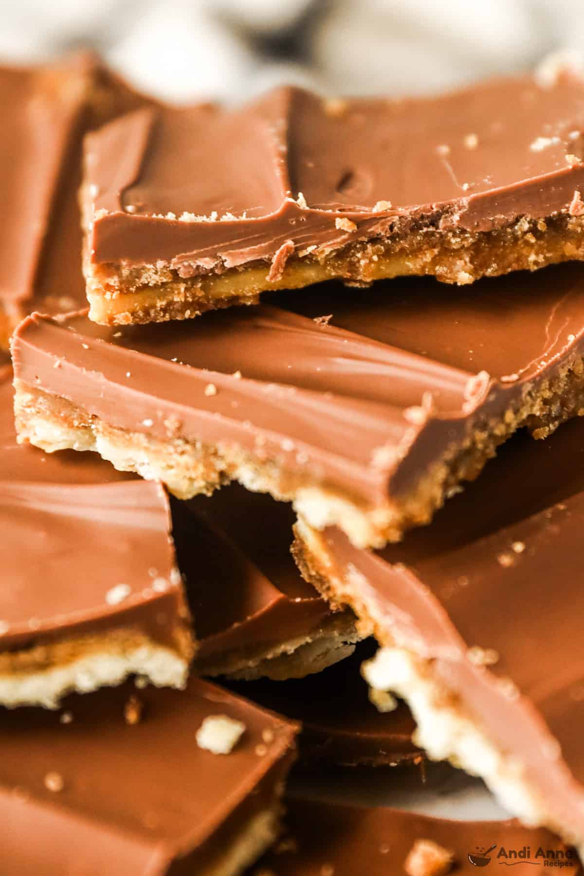 Pile of saltine cracker candy pieces on a plate showing the chocolate top and crunchy toffee cracker layers.