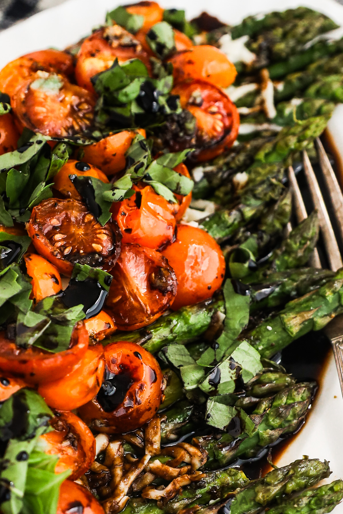 Close up of cherry tomatoes, basil and asparagus with balsamic sauce drizzled on top