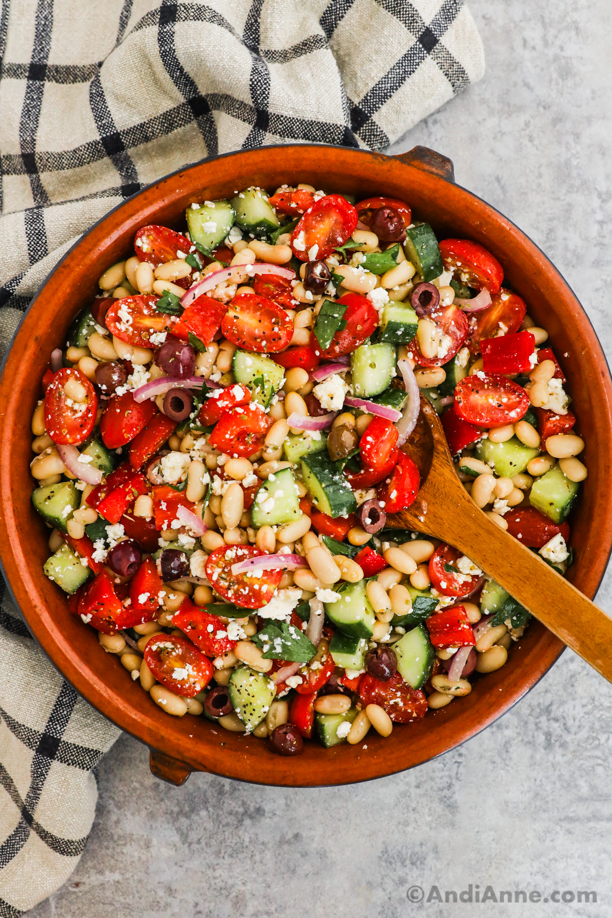 Close up of mediterranean white bean salad with chopped cucumber, tomatoes, red onion and feta cheese in a large serving bowl.