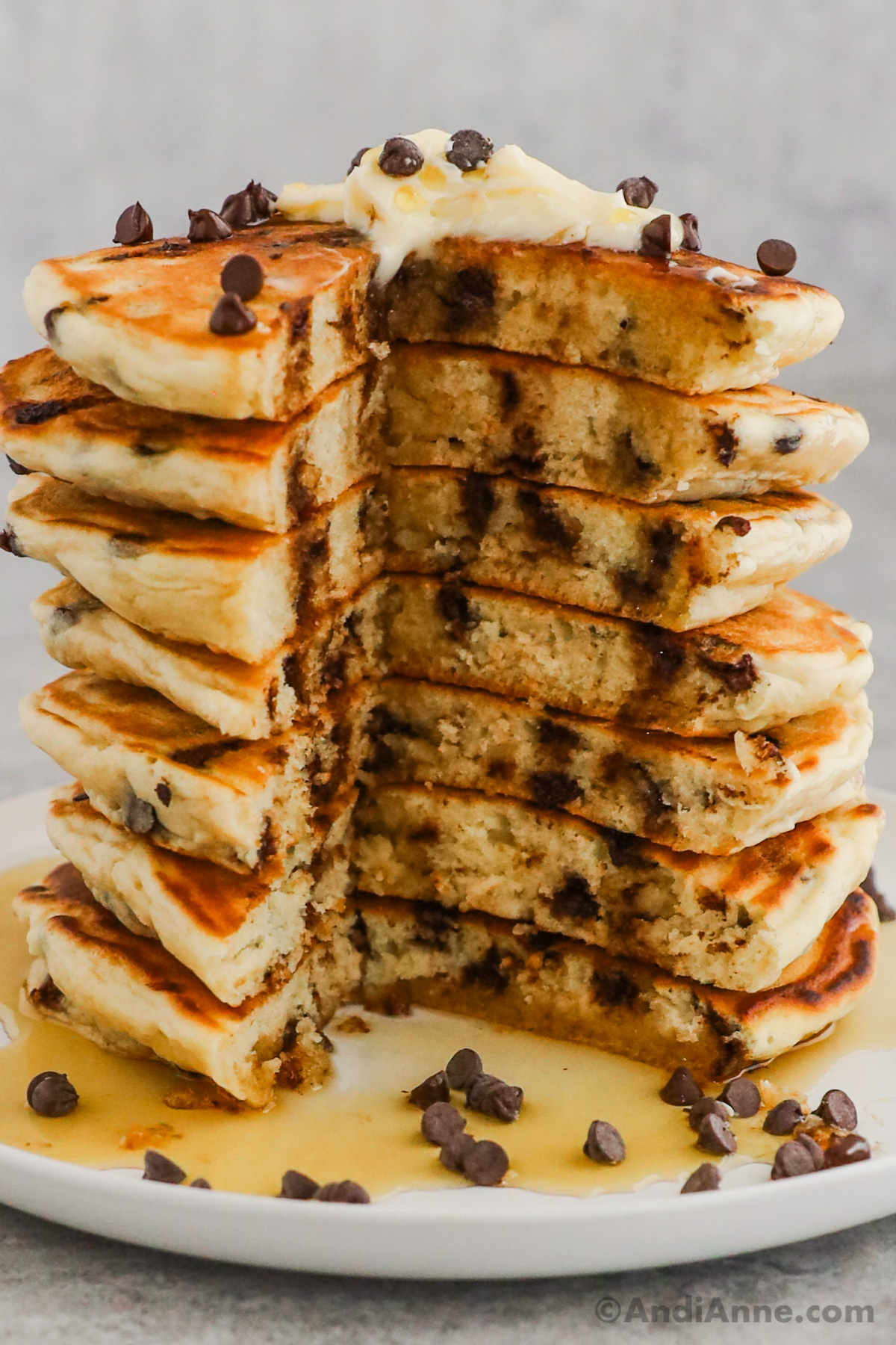 Stack of chocolate chip pancakes with a large slice cut out of them all so that you can see the fluffy chocolatey insides