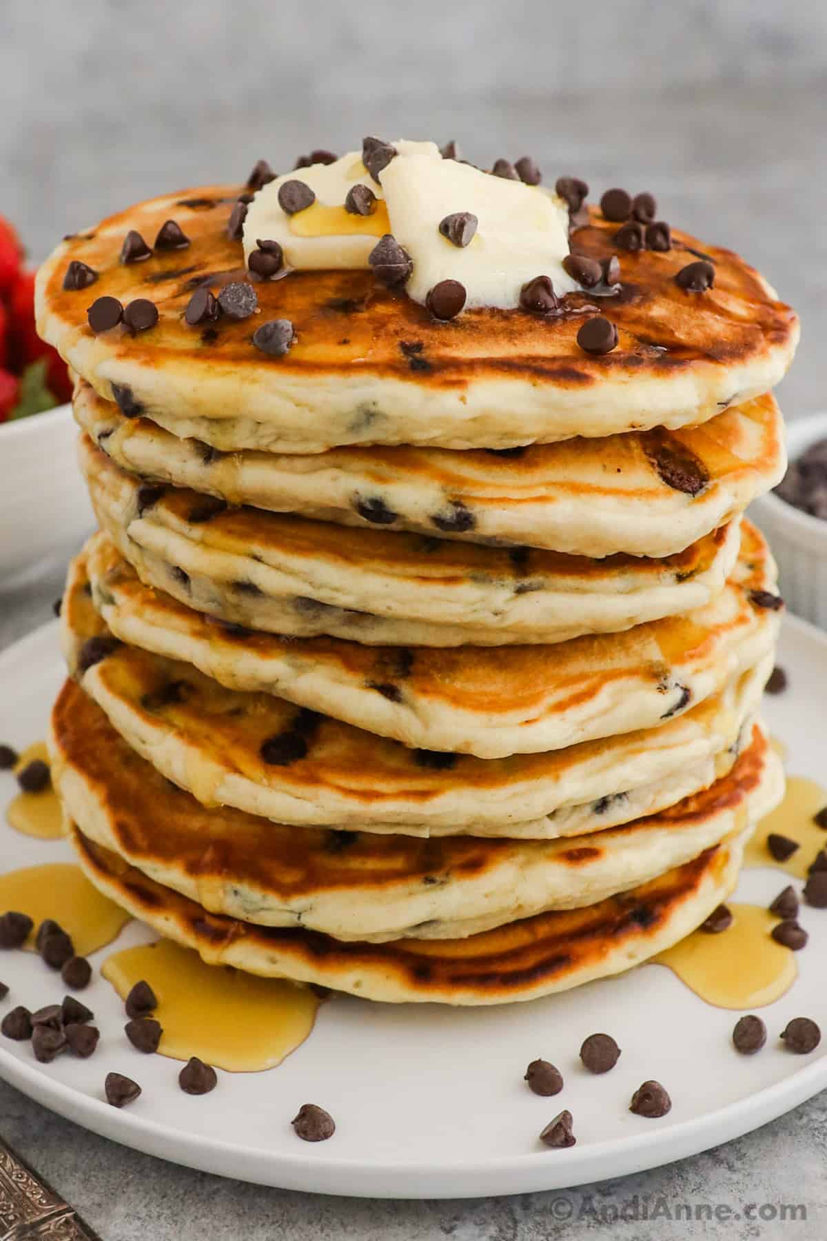 A stack of chocolate chip pancakes topped with butter, maple syrup and mini chocolate chips