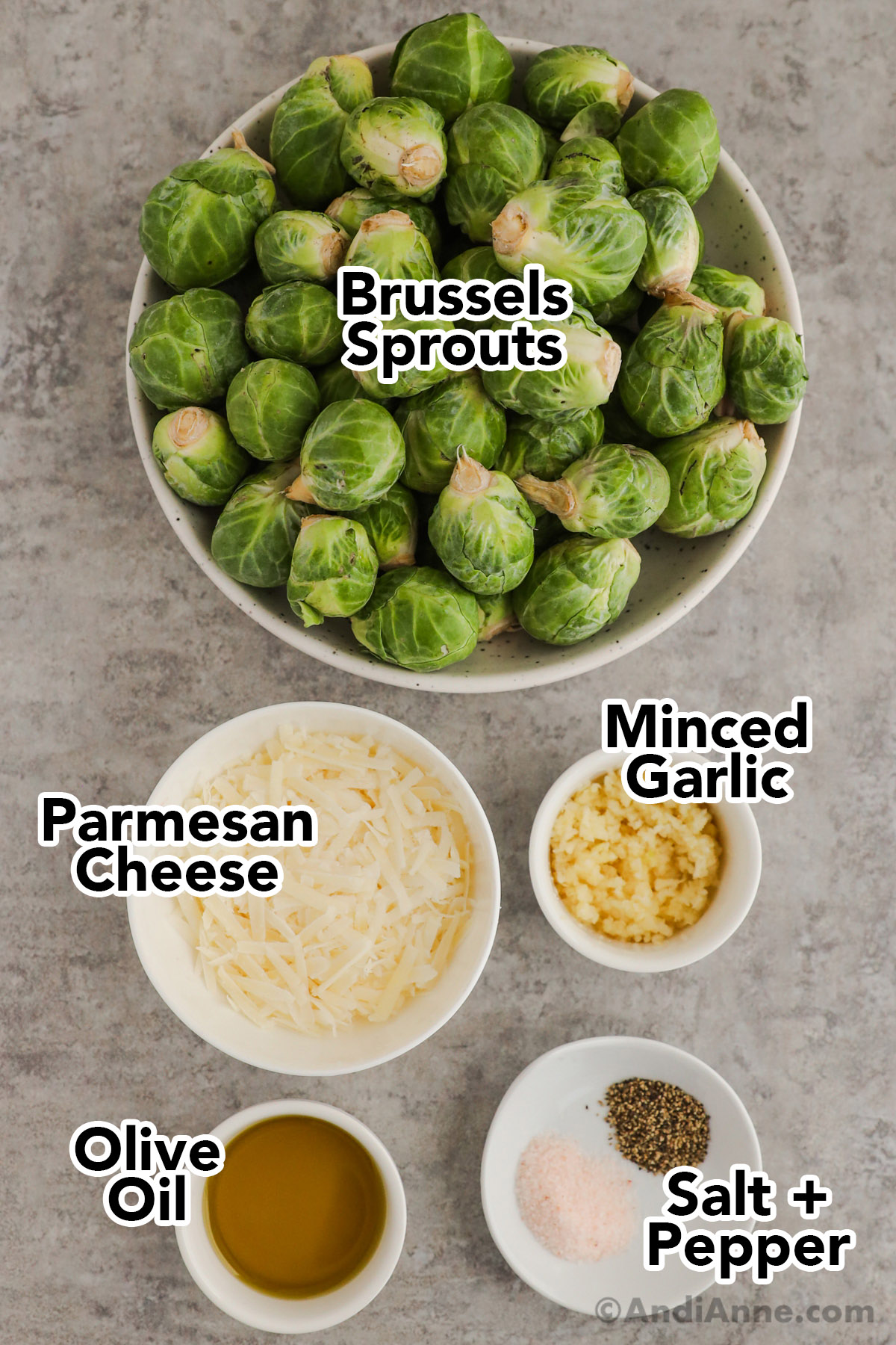 A bowl of brussels sprouts, and bowls of parmesan cheese, minced garlic, olive oil, salt and pepper.