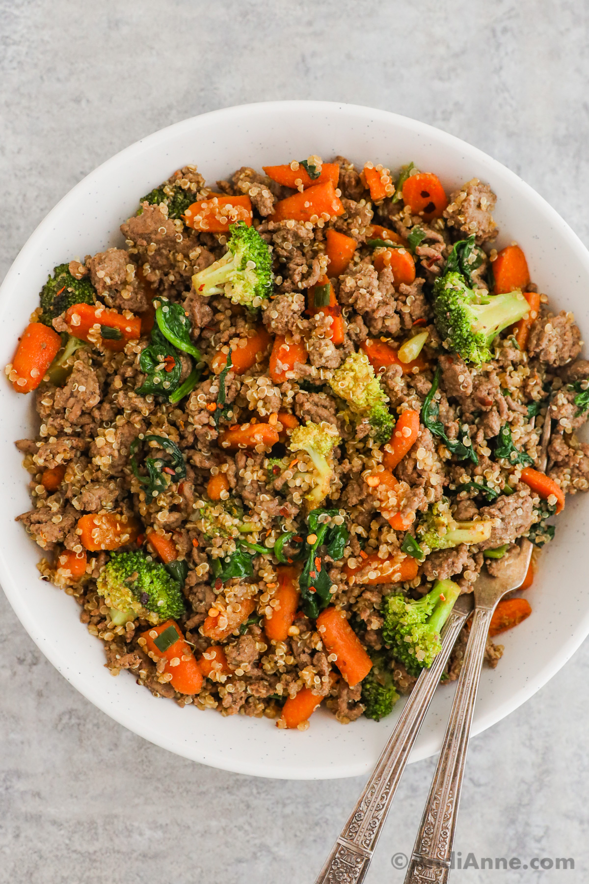 Close up of ground beef, quinoa, broccoli, carrots and spinach stir fry in a bowl.