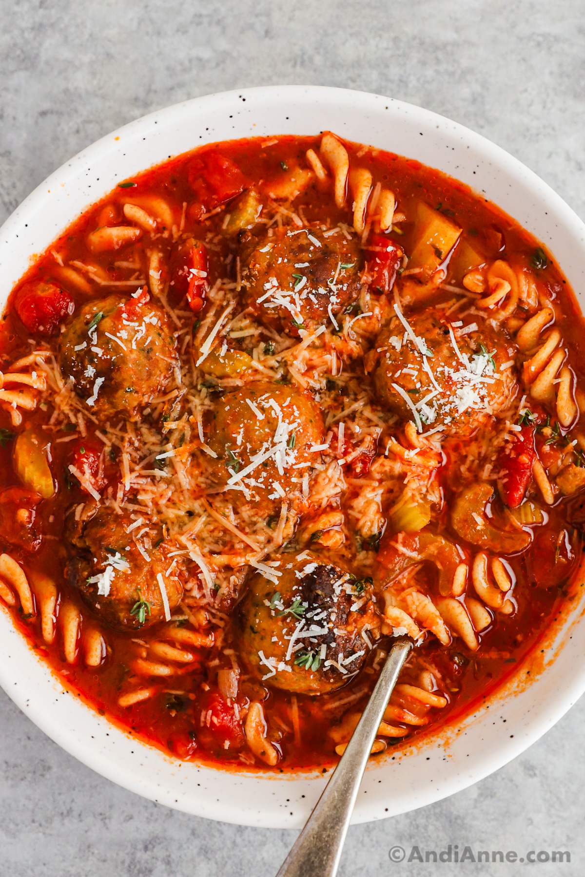 A bowl of italian meatball soup with grated parmesan on top