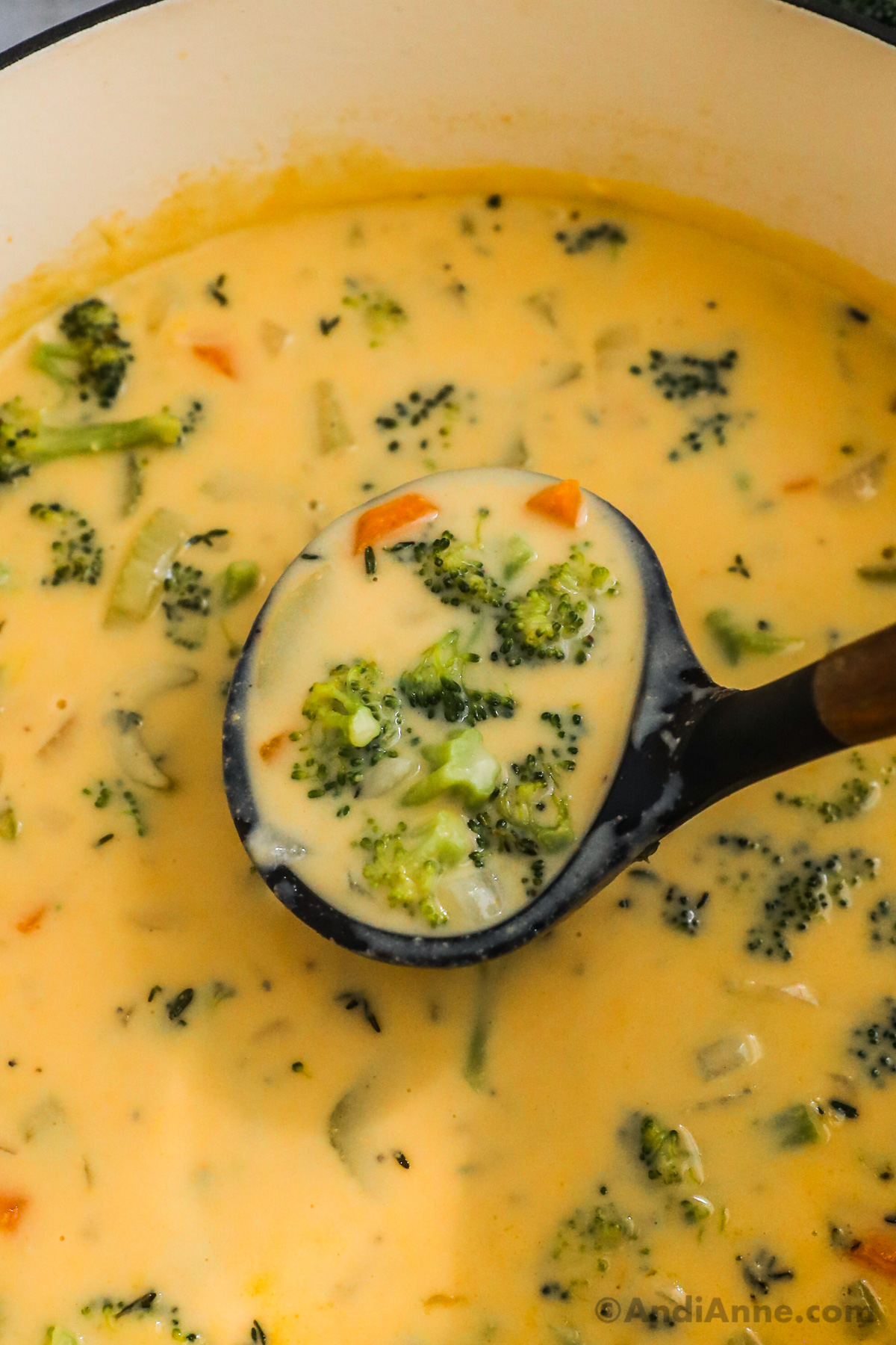 Soup ladle scooping broccoli cheddar soup close up.